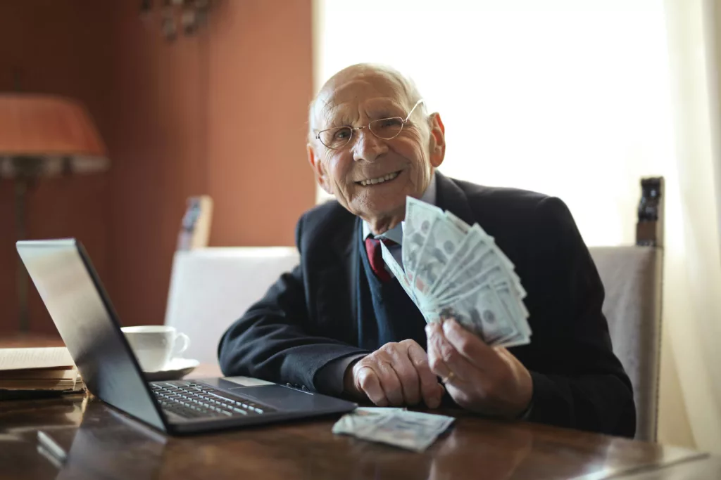 the side hustle, older man with a laptop and money